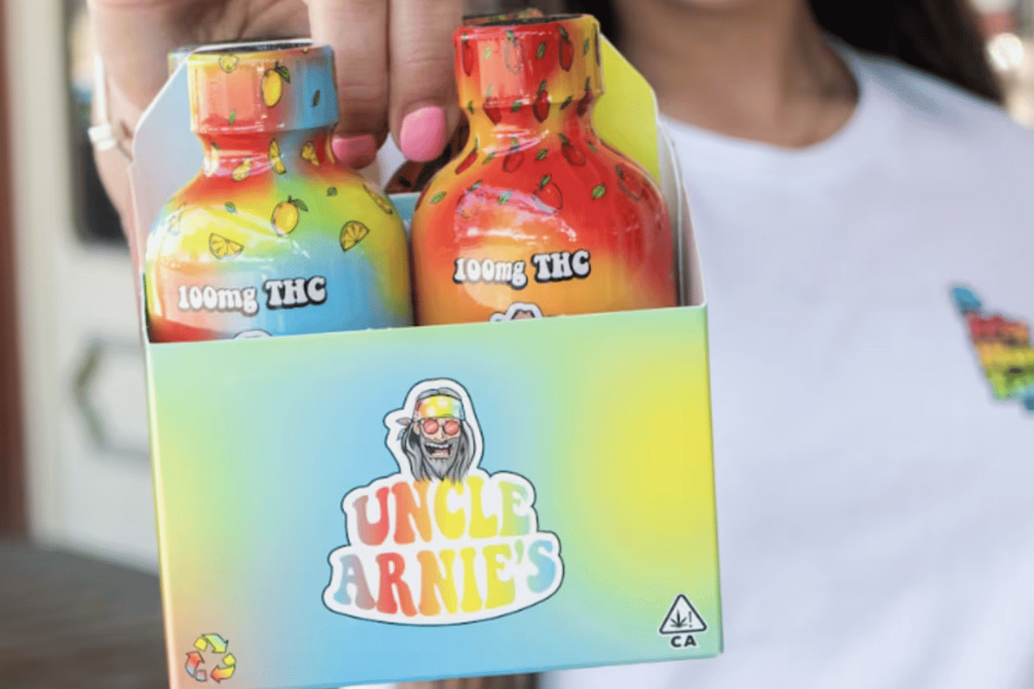 A vibrant Uncle Arnie's subscription box held by a customer, showcasing colorful cannabis-infused beverages.