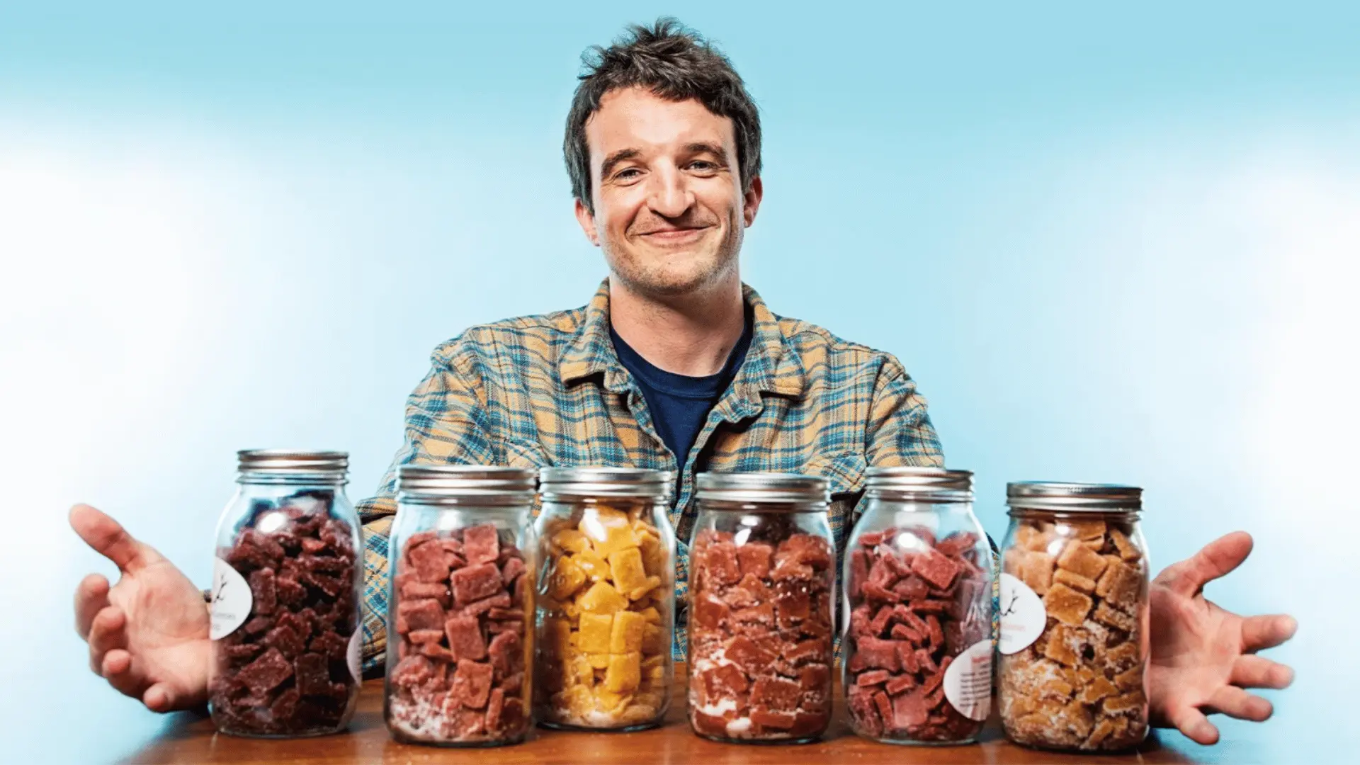 A smiling individual with jars of Wyld cannabis gummies in assorted flavors and colors, representing the brand's dedication to quality and innovation.