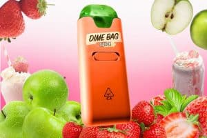 An orange Dime Bag Switch 3-in-1 vape device with a green top, surrounded by fresh strawberries, green apples, and a creamy strawberry milkshake. The background features a gradient pink and white tone, enhancing the fruity and dessert-inspired theme.