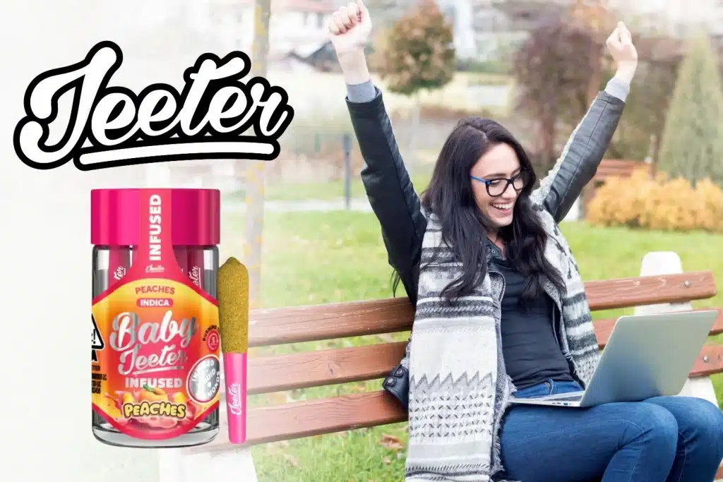 A joyful woman sitting on a park bench, raising her arms in excitement while looking at her laptop. The Jeeter logo is displayed in bold, black script on the left side. Below it, the Baby Jeeter Peaches Infused product is showcased, featuring vibrant pink packaging with a peach-themed design and a coated pre-roll beside the jar. The background captures an autumn-like outdoor setting, enhancing the feeling of relaxation and happiness. 