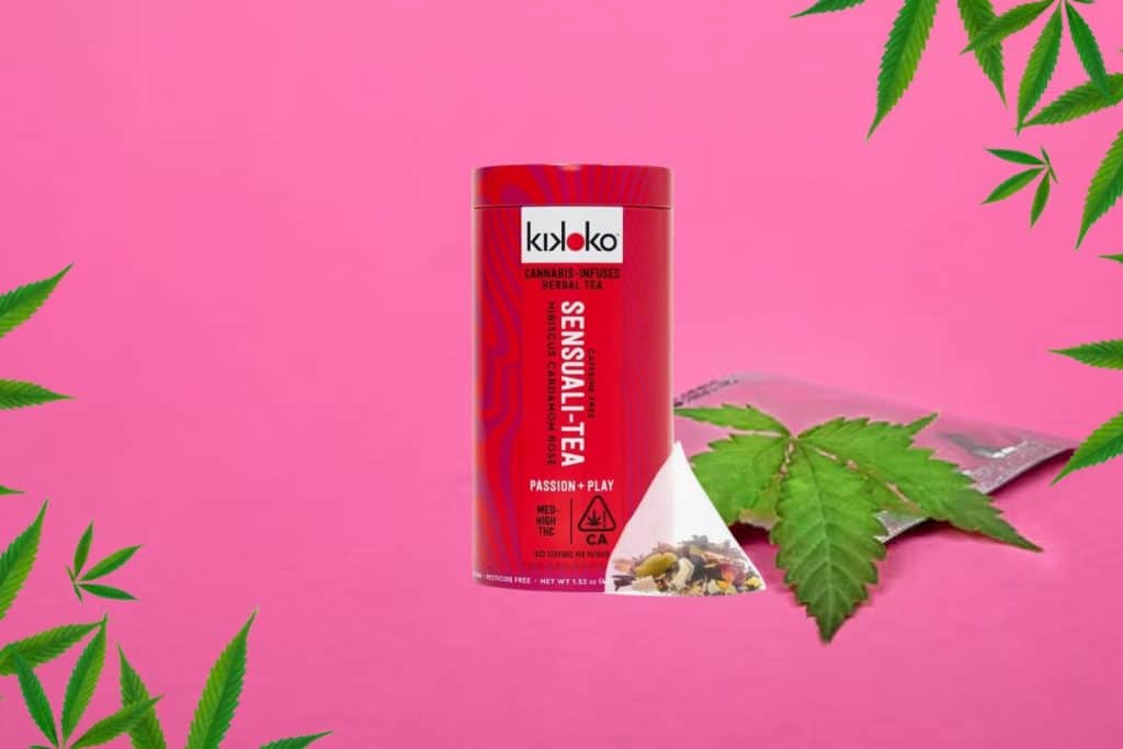 Kikoko Sensuali-Tea cannabis-infused herbal tea in a red tin, with a pyramid tea bag filled with herbs, set against a vibrant pink background with cannabis leaves and a sealed package.